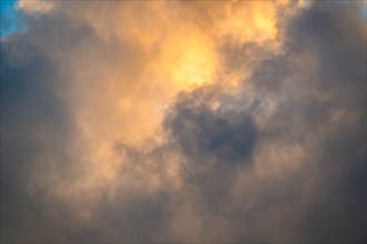 Golden and gray Cumulus clouds on sky at sunset
