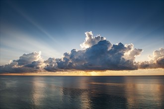 Clouds and sunlight above ocean at sunrise