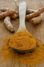 Turmeric powder and root on wooden surface