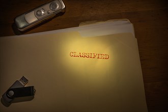 Folder marked Classified with spy camera and thumb drive