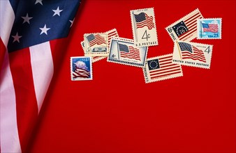 Retro postage stamps and American flag against red background