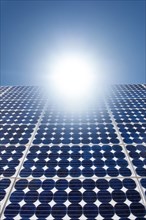 Solar panels with bright sunburst in blue sky