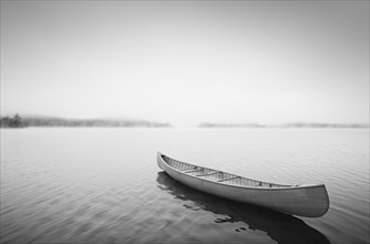 Wooden canoe floating on calm lake surface at sunrise
