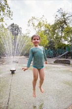 Girl jumping in sprinklers