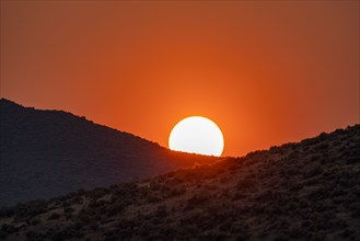 Sun setting behind hills