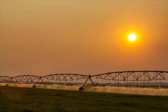 Irrigation equipment in field at sunset
