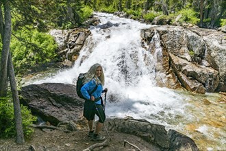 Woman hiking by mountain waterfall