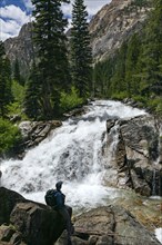 Man hiking by mountain waterfall