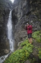 Hiker taking picture near waterfall