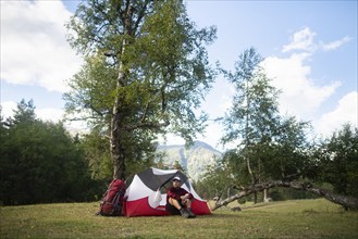 Hiker sitting by tent in mountains