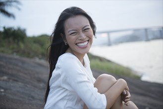 Smiling woman sitting on riverbank