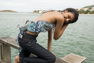 Woman kneeling on banister overlooking harbor