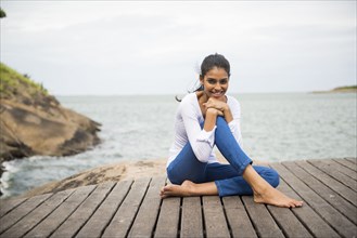 Woman sitting on wooden deck overlooking lake