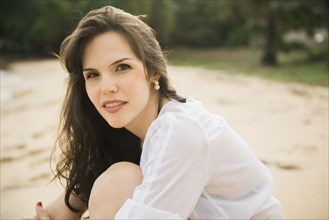 Smiling Caucasian woman sitting on beach