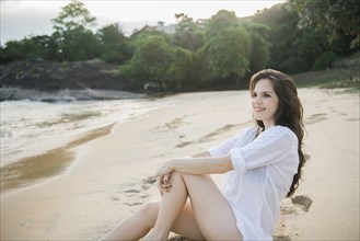 Smiling Caucasian woman sitting on beach