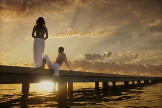 Caucasian couple admiring sunset from dock over ocean