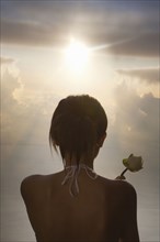 Chinese woman holding rose under dramatic sky