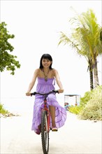 Chinese woman riding bicycle on tropical beach