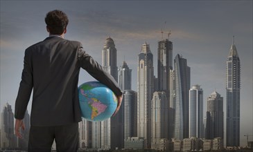 Caucasian businessman holding globe near Qatar cityscape
