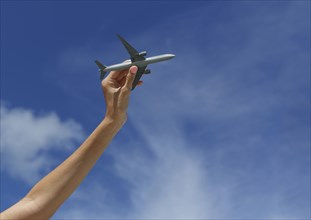 Caucasian woman playing with toy airplane under blue sky