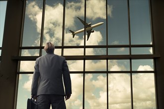 Caucasian businessman admiring airplane from airport windows