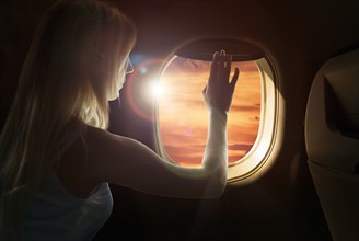 Caucasian woman admiring sunset from airplane window