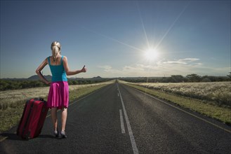 Caucasian woman hitchhiking on remote road