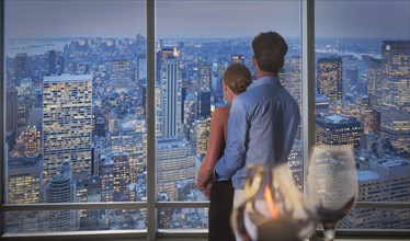 Caucasian couple admiring New York cityscape from window