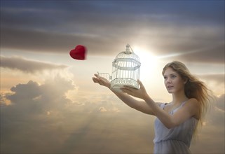 Caucasian woman releasing heart from birdcage