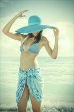Caucasian woman wearing bikini and sun hat on beach