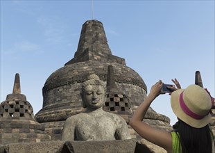 Tourist photographing Buddha statue on Temple of Borobudur