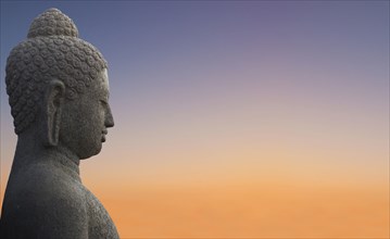 Close up of Buddha statue under sunset sky