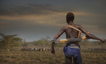 Black soldier carrying gun in open field