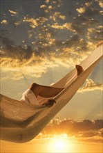 Caucasian woman laying in hammock at sunset
