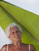 Older Caucasian woman standing under leaf