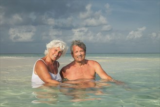Older Caucasian couple swimming on beach