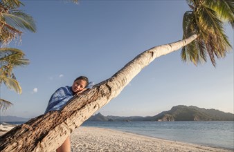 Asian woman on palm tree on beach