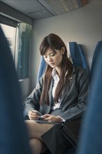 Chinese businesswoman using cell phone on airplane