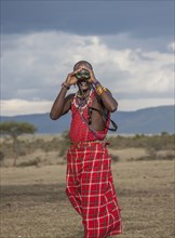 Black man in traditional clothing using binoculars