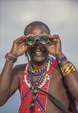 Black man in traditional clothing using binoculars