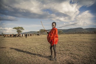 Black boy in traditional clothing standing in remote field