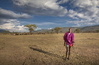 Black man in traditional clothing standing in remote field