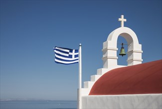 Greek flag and bell arch under blue sky