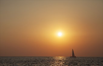 Sailboat sailing on ocean horizon at sunset