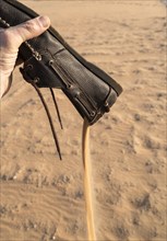 Hand pouring sand from shoe in desert