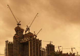 Low angle view of cranes constructing Doha highrise buildings