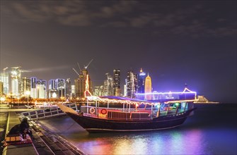 Illuminated boat docked in Doha harbor