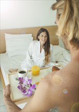 Caucasian man serving woman breakfast in bed