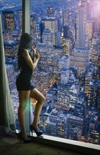 Chinese woman admiring cityscape at night from window