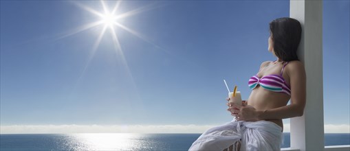 Caucasian woman drinking cocktail at ocean